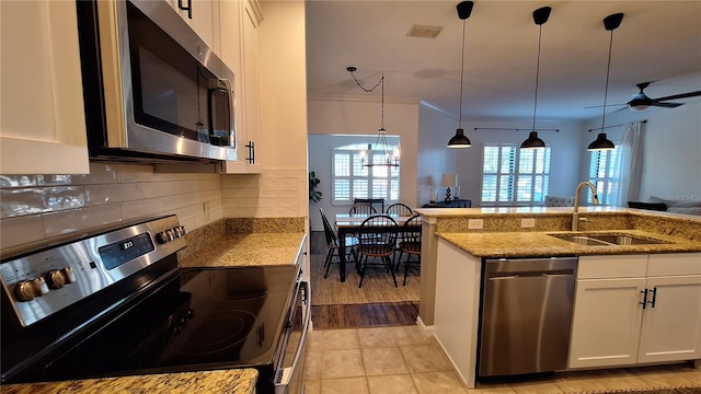 kitchen featuring white cabinets, appliances with stainless steel finishes, pendant lighting, and sink