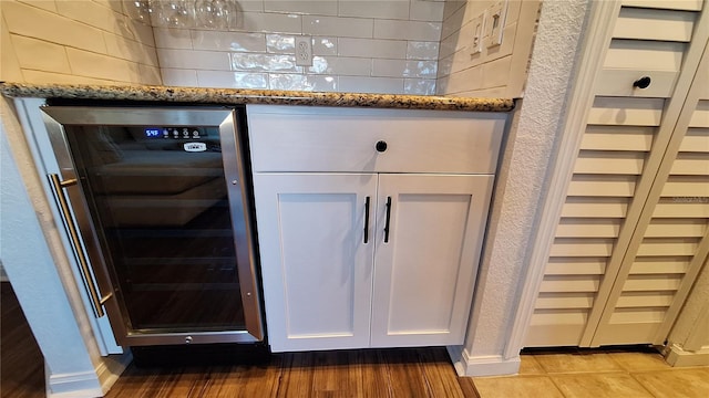 details with white cabinets, light hardwood / wood-style flooring, beverage cooler, and dark stone counters