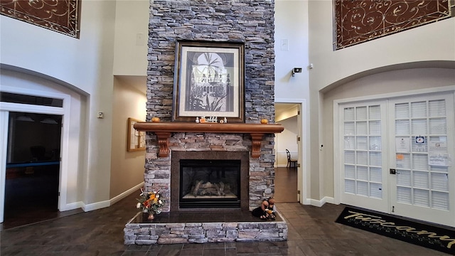 living area with a stone fireplace and a towering ceiling