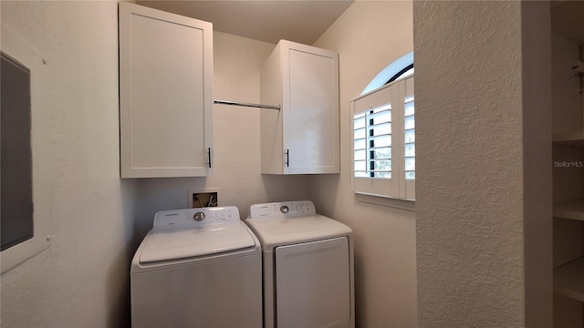 clothes washing area featuring cabinets and separate washer and dryer