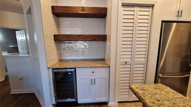 kitchen featuring white cabinets, beverage cooler, light stone countertops, and stainless steel refrigerator