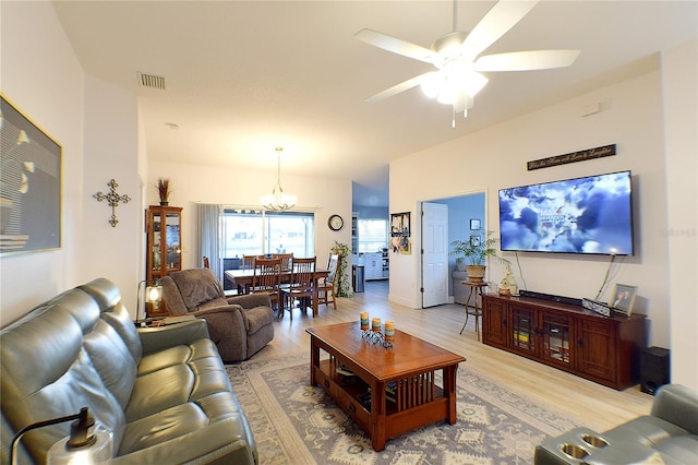 living room with ceiling fan with notable chandelier and hardwood / wood-style flooring