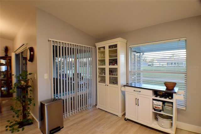 kitchen featuring white cabinets, light hardwood / wood-style floors, and vaulted ceiling