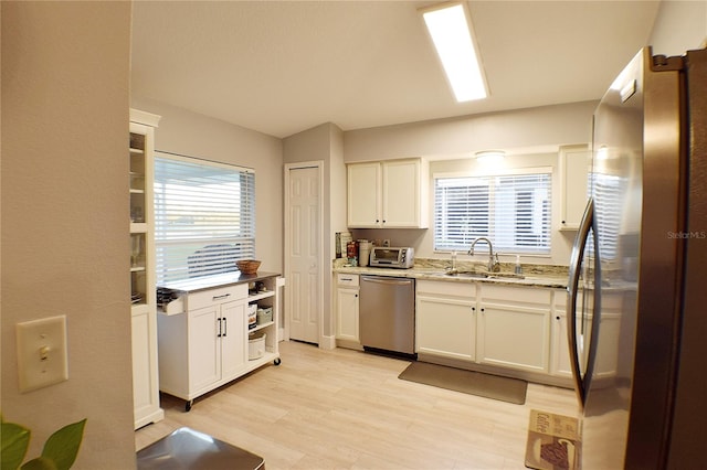 kitchen featuring sink, light wood-type flooring, appliances with stainless steel finishes, light stone counters, and white cabinetry