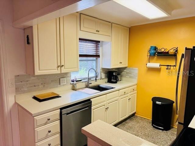 kitchen with backsplash, stainless steel dishwasher, fridge, and sink