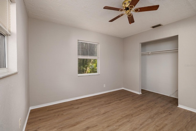 unfurnished bedroom with ceiling fan, hardwood / wood-style floors, a closet, and a textured ceiling