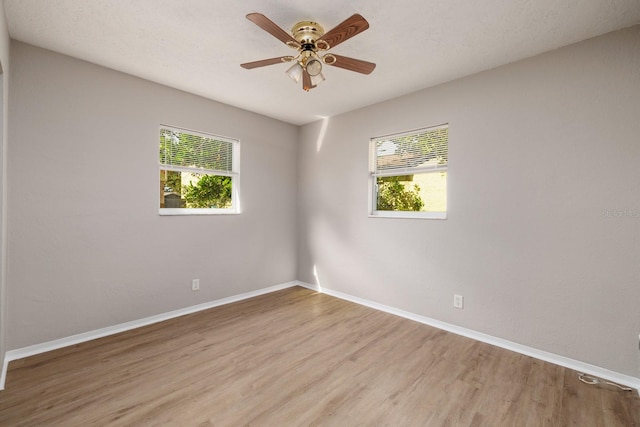 unfurnished room featuring wood-type flooring, a healthy amount of sunlight, and ceiling fan