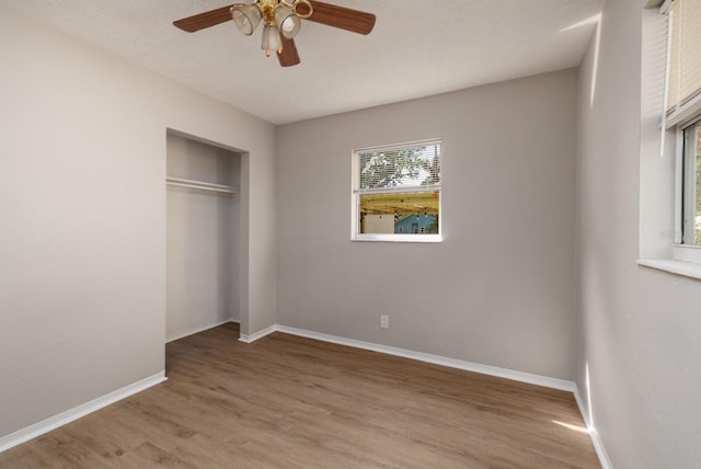 unfurnished bedroom featuring multiple windows, ceiling fan, light hardwood / wood-style floors, and a closet