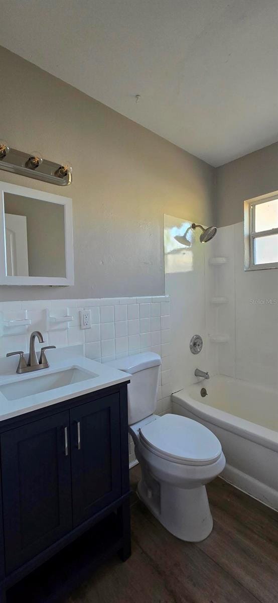 full bathroom featuring shower / tub combination, wood-type flooring, tile walls, vanity, and toilet