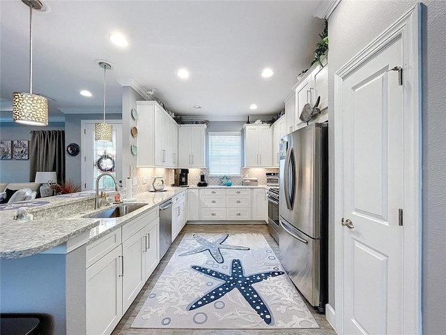 kitchen featuring sink, ornamental molding, appliances with stainless steel finishes, decorative light fixtures, and kitchen peninsula