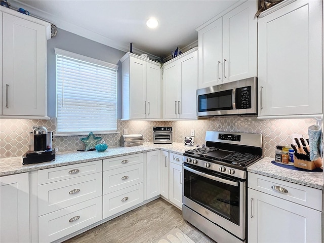 kitchen featuring white cabinets, light stone countertops, stainless steel appliances, and tasteful backsplash