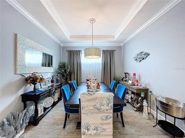 dining room with ornamental molding, a tray ceiling, and light hardwood / wood-style flooring