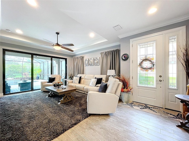 living room featuring ceiling fan, plenty of natural light, crown molding, and light wood-type flooring