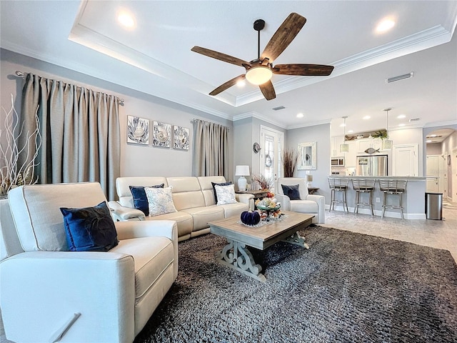 living room featuring a raised ceiling, ceiling fan, and crown molding