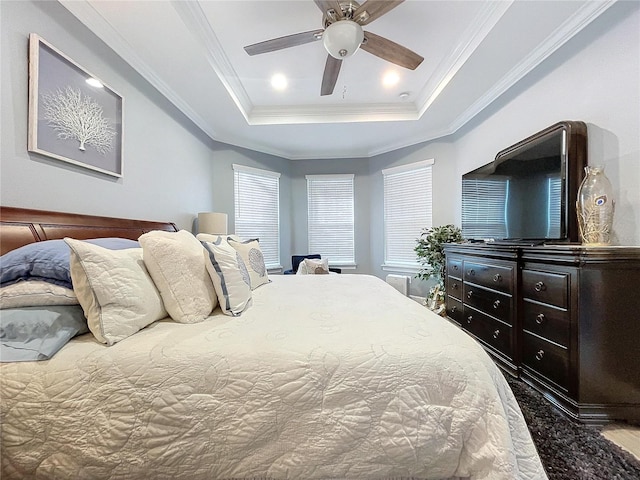 bedroom with a raised ceiling, ceiling fan, wood-type flooring, and ornamental molding