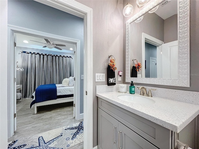 bathroom with vanity, hardwood / wood-style flooring, ceiling fan, and ornamental molding