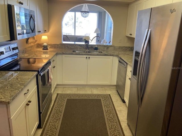 kitchen with white cabinetry, sink, stainless steel appliances, kitchen peninsula, and light tile patterned floors