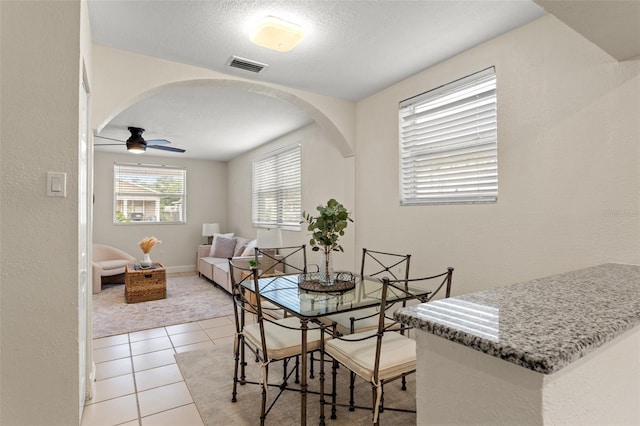 tiled dining room with ceiling fan and a textured ceiling