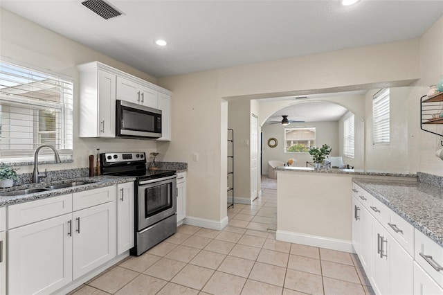 kitchen with light stone counters, stainless steel appliances, ceiling fan, sink, and white cabinets