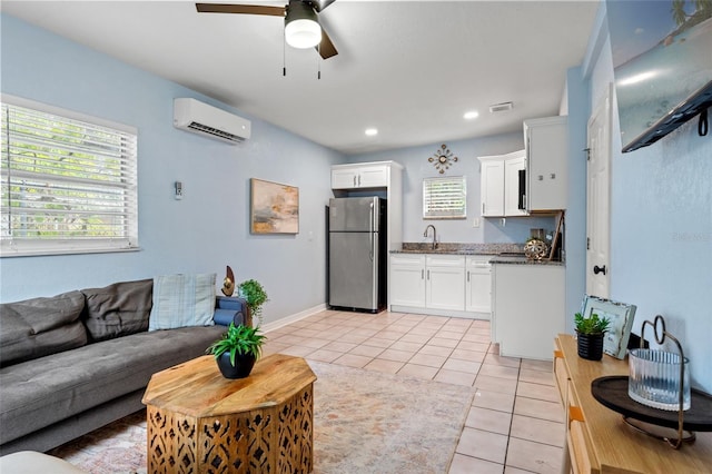 living room featuring a wall unit AC, ceiling fan, and light tile patterned floors