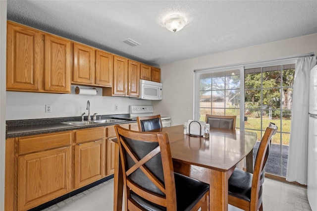 kitchen featuring a textured ceiling, white appliances, and sink