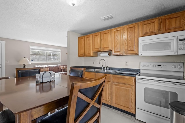 kitchen featuring a textured ceiling, white appliances, and sink