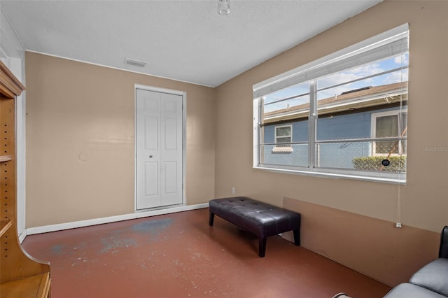 bedroom with a textured ceiling, a closet, multiple windows, and concrete floors