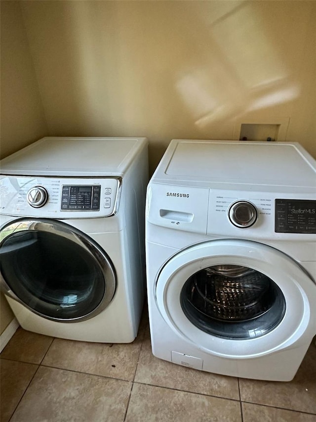 clothes washing area with light tile patterned floors and washer and clothes dryer