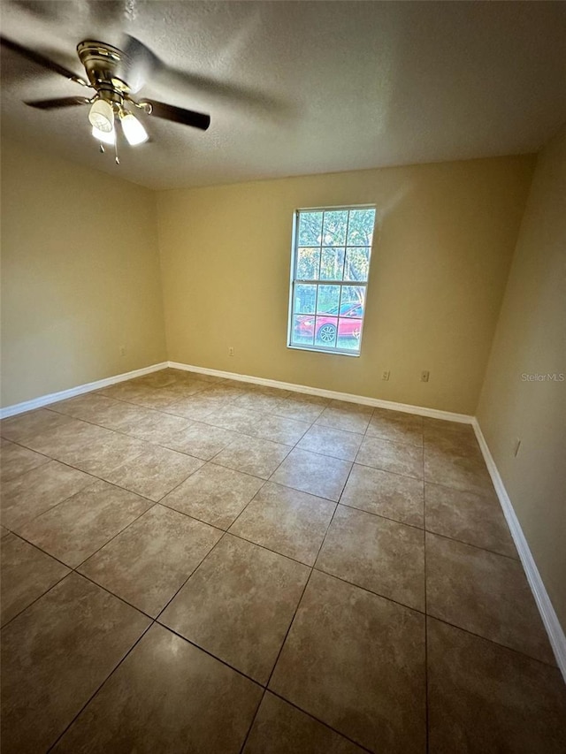 empty room featuring a textured ceiling, tile patterned floors, and ceiling fan