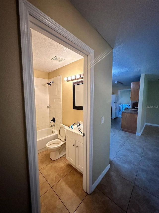 full bathroom with tile patterned floors, vanity, a textured ceiling, tiled shower / bath combo, and toilet