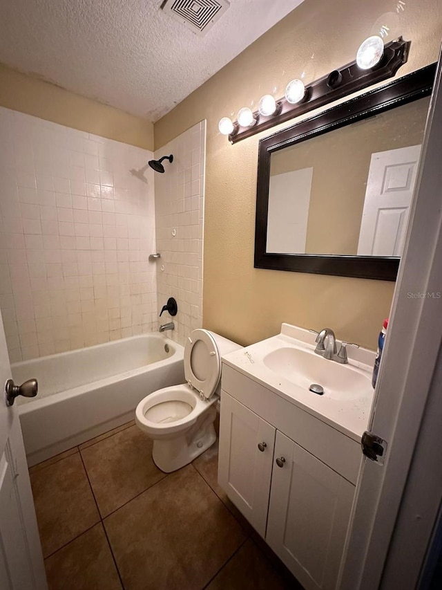 full bathroom featuring vanity, tiled shower / bath, tile patterned flooring, toilet, and a textured ceiling