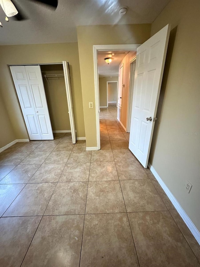 unfurnished bedroom with ceiling fan, light tile patterned floors, and a closet