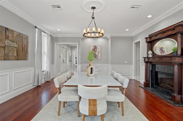 dining area with a fireplace, dark hardwood / wood-style flooring, an inviting chandelier, and ornamental molding