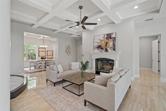 living room with light wood-type flooring, ornamental molding, coffered ceiling, ceiling fan with notable chandelier, and beamed ceiling