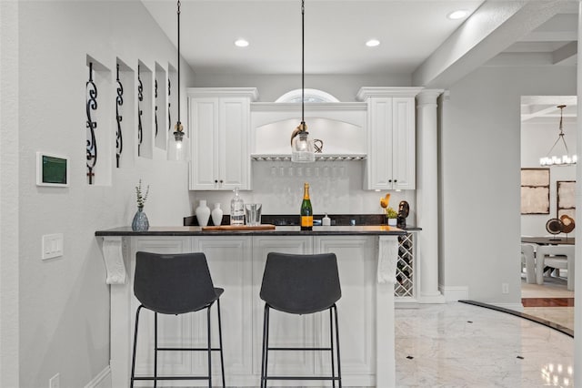 kitchen featuring a kitchen bar, white cabinets, and hanging light fixtures