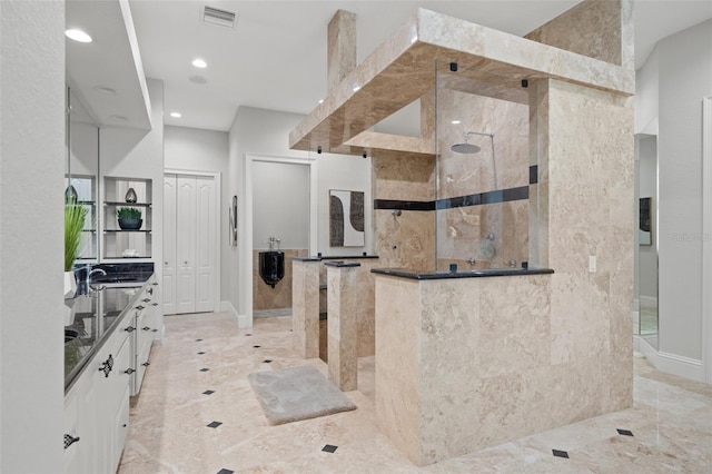 bathroom with a tile shower and vanity