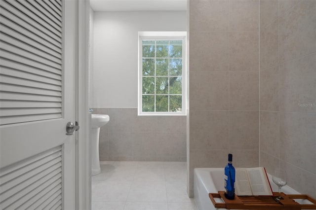 bathroom with a washtub, tile patterned floors, and tile walls