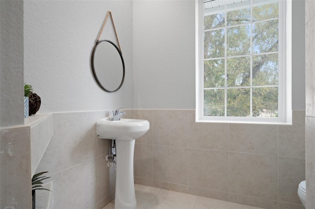 bathroom featuring tile patterned floors, plenty of natural light, tile walls, and toilet