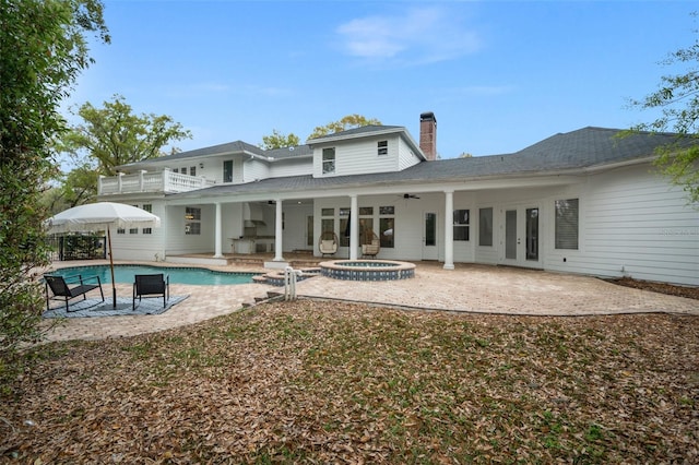 back of property featuring french doors, a balcony, a pool with hot tub, ceiling fan, and a patio area