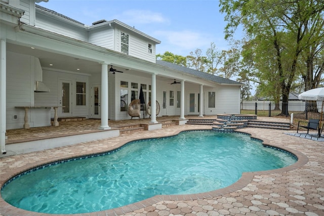 view of swimming pool with ceiling fan, a patio, and french doors