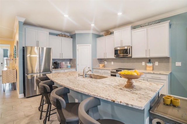 kitchen featuring a breakfast bar, stainless steel appliances, a kitchen island with sink, sink, and white cabinets