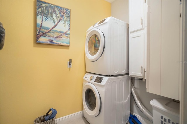 laundry room featuring stacked washer and dryer and cabinets