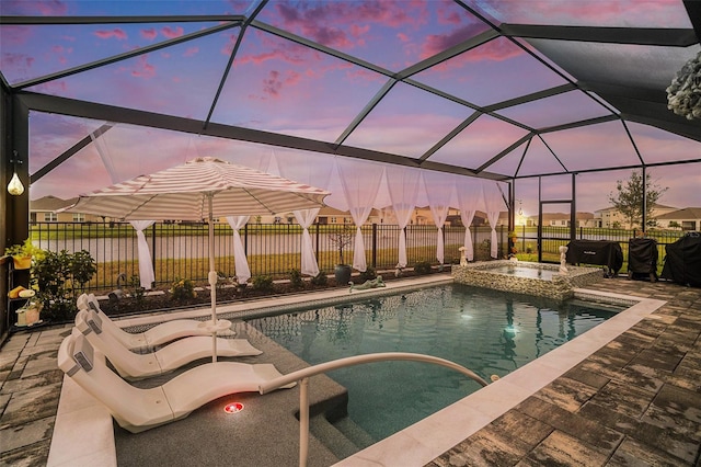 pool at dusk with a patio area, a lanai, and an in ground hot tub