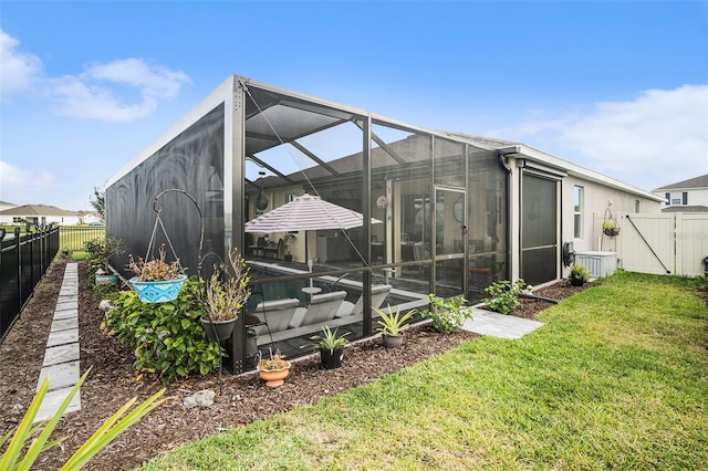 back of house featuring a yard and glass enclosure