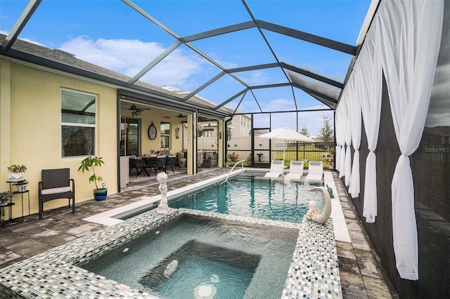 view of pool featuring glass enclosure, ceiling fan, a patio, and an in ground hot tub