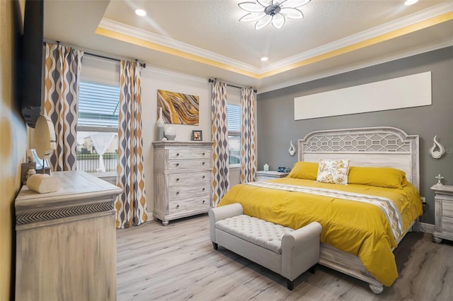 bedroom with a raised ceiling, crown molding, light hardwood / wood-style floors, and a textured ceiling