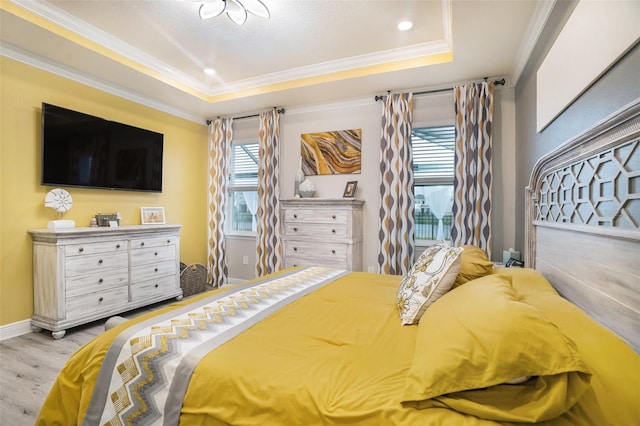 bedroom featuring light wood-type flooring, a tray ceiling, and ornamental molding