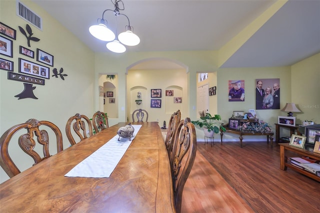 dining space with dark hardwood / wood-style floors and a notable chandelier