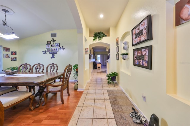 dining space featuring light tile patterned floors, lofted ceiling, and a notable chandelier