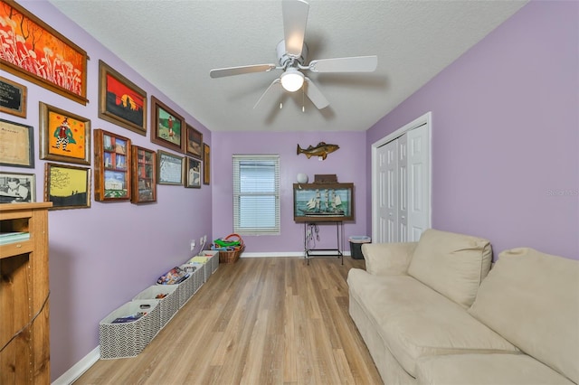 sitting room featuring a textured ceiling, light wood-type flooring, and ceiling fan